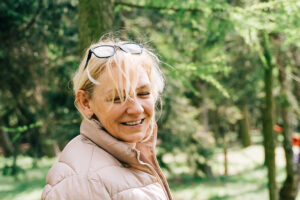 Image of a woman recovering from domestic abuse in a forest smiling and happy